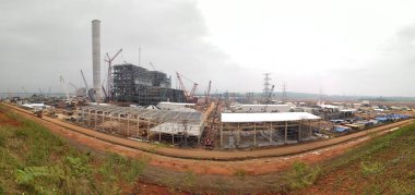 Buhar santrali binaları, endüstriyel binalar, kargo gemilerinin açık hava sahasının altında demirlediği işlek nakliye limanının yakınında akşam saatlerinde ışıl ışıl parlıyor..