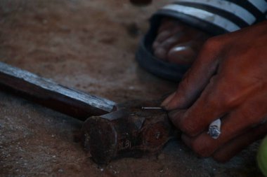 Bir marangoz demir bir çivi hazırlar demir bir çekiç üzerindeki demir çiviyi tamir etmeye çalışır..