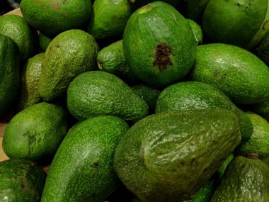 Taze organik yeşil bir avokado, beyaz bir zemin üzerinde doğal bir vejetaryen diyeti için sağlıklı bir tropikal bileşen olarak izole edilir.