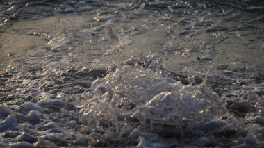 Kıyıya vuran okyanus dalgaları yakın mesafede, altın saatte ele geçirildi. Su damlacıkları hareket halinde donarak dinamik bir doku oluşturur. Parıldayan röfleler ve sakin bir deniz havası..