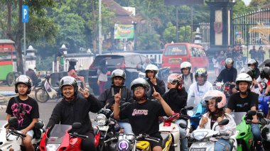 Şehir sokaklarında kask takan hevesli bir grup motosikletçi bisiklet ve toplum ruhuna olan tutkularını sergiliyorlar. Dumanla canlı toplanan Batang, Endonezya, 23 Mart 2025