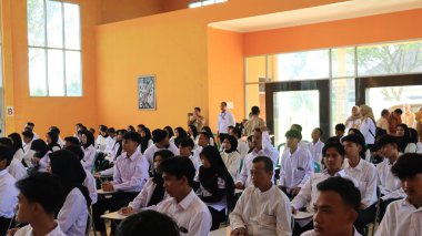 Yüzlerce öğrenci ferah bir salonda düzenli bir şekilde otururken, denetimciler oturumu sakin bir akademik atmosferde, Pekalongan, 27 Temmuz 2025 'te izlerken yazılı bir sınava konsantre oluyorlar.