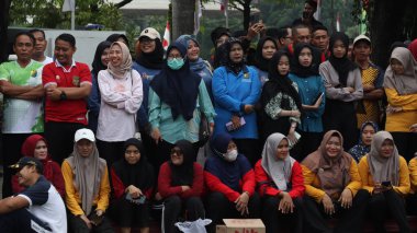 Bir grup insan bir parkta çimlerin üzerinde oturuyor. Rahatlıyorlar ve 14 Ağustos 2025 'te Pekalongan Endonezya' da bir gösteri veya yarışma izliyorlar.