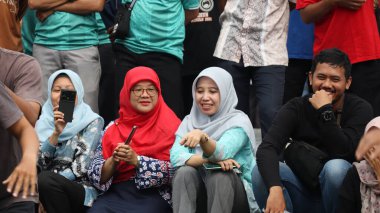 Bir grup insan bankta oturuyor, biri gülüyor. Sahne neşeli ve dost canlısı, Pekalongan Endonezya, 14 Ağustos 2025