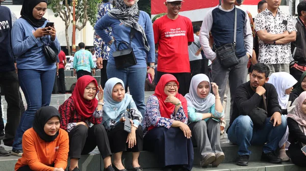 Bir grup insan bir parkta çimlerin üzerinde oturuyor. Rahatlıyorlar ve 14 Ağustos 2025 'te Pekalongan Endonezya' da bir gösteri veya yarışma izliyorlar.