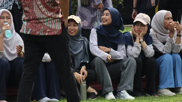 Bir grup insan bankta oturuyor, biri gülüyor. Sahne neşeli ve dost canlısı, Pekalongan Endonezya, 14 Ağustos 2025