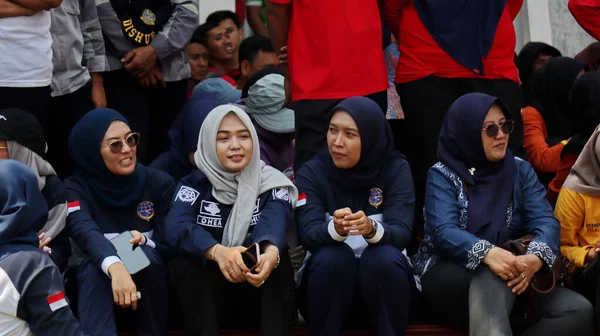 Bir grup insan bankta oturuyor, biri gülüyor. Sahne neşeli ve dost canlısı, Pekalongan Endonezya, 14 Ağustos 2025