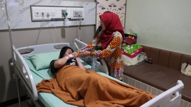 İnsanlar hastane yatağında dinlenen bir hastanın etrafında toplandı. Sahnede bir hastane ziyareti, destek ve sağlık hizmetleri etkileşimi, Pekalongan, Endonezya, 21 Mayıs 2025
