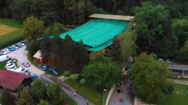 Slovenya 'nın Domzale kentindeki yazlık tiyatro stüdyosunun hava görüntüsü, etkinlik için dışarıda toplanan insanları gösteriyor. Yavaş çekim.
