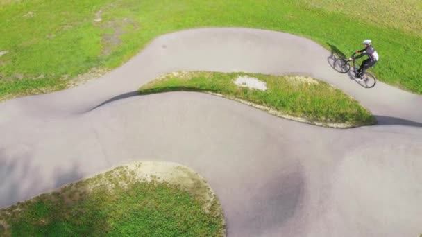 スロベニアのDomzaleの公園でポンプトラックで自転車をレースするサイクリングギアの男の空の鳥の目のビュー — ストック動画