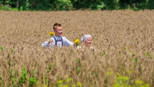 Zwei Kinder Hüpfen Mit Sonnenblumen Durch Das Weizenfeld — Stockvideo