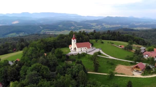 背景としての町や山の風景 ドローンの傾きを持つヨーロッパの村の教会の空中フォローフォーカス映像 — ストック動画
