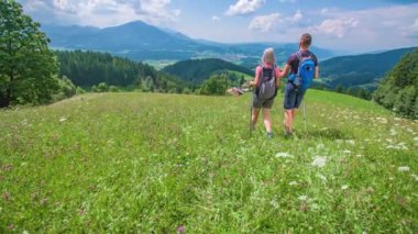 Slovenya 'nın dağlarındaki kır çiçeklerinin arasında genç çiftler yürüyüş yapıyor.