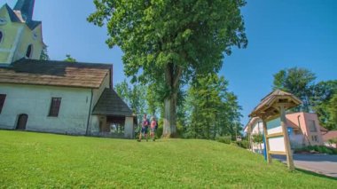 Geniş açı, tarihi kilise bahçesinde yürüyüş yapan genç çifti takip ediyor..