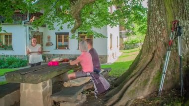 Yaşlı kadın dışarıdaki bir çifte büyük bir tabak yemek servis ediyor.