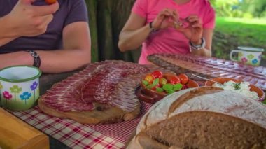 Kadın, Lesnik 'teki bir turist çiftliğinde ağacın altında doğal ekolojik ev yemekleri yiyor. Slovenya.