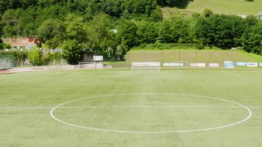 Güneşli bir günde boş bir futbol sahasının alçak drone görüntüsü. Kimse yok..