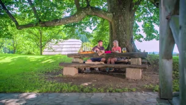 Молоді Коханці Діляться Обідом Під Деревом Біля Старого Колодязя Межами — стокове відео