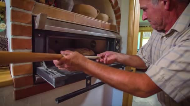 Elderly Man Pulls Freshly Baked Bread Out Oven Wooden Shovel — Stock Video