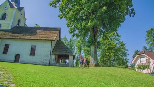 Pasangan Hiker Melewati Depan Gereja George Slovenia Gradec Slovenia — Stok Video