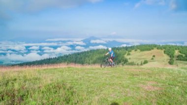 Yavaş çekim, beyaz elbiseli ve kask takan beyaz bir çift. Bisikletle yokuş yukarı, statik geniş açı.