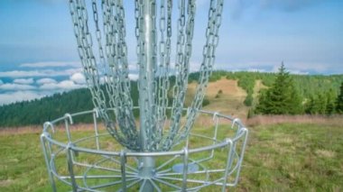 Frizbi diski zincirli bir golf topu sepetine konuyor.