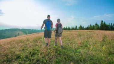 Sırt çantalı genç turistlerin doğa yürüyüşü yaparken yavaş çekim..