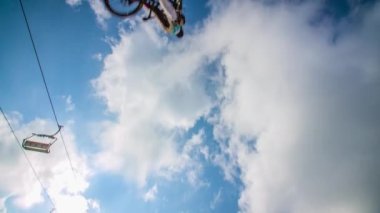 Bisikletli bir genç bisikletle küçük bir tepenin üzerinden atlıyor. Güzel, güneşli bir gün..