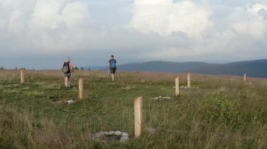 Maceraperest bir sırt çantalı çift sabahın erken saatlerinde bulutlar ve büyüleyici arka plan manzarasıyla güzel yeşil dağları geziyor / geziyor..