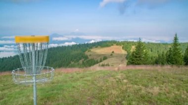 Bir frizbi, güzel manzaranın önüne golf sepetine konar.