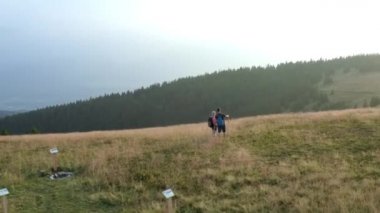 Maceraperest bir sırt çantalı çift sabahın erken saatlerinde güzel yeşil dağlara tırmanıyor ve doğaya hayran kalıyorlar. Hava aracı görüntüleri..