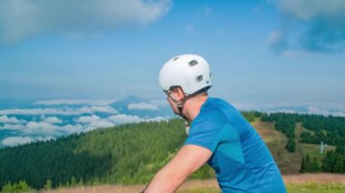 Bisikletli adam tepeden manzaranın tadını çıkarıyor.