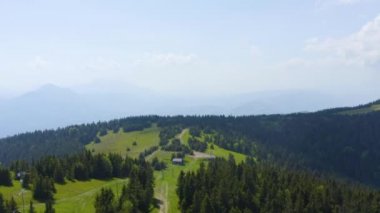 Slovenya 'nın Kope Kayak Tatil Köyü' ndeki tepeden aşağıya bakan kayak pistinin arka planında dağlar olan havadan görüntüsü, İHA üstgeçişi görüntüsü
