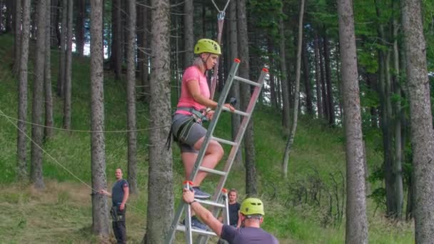 若い女性の木の間に大きなぶら下げスイングに到達するための階段を登る スローモーション — ストック動画