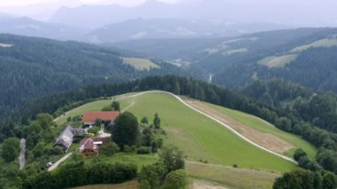 Slovenya 'nın Prevalje kentinin uzak doğasındaki tepenin üzerindeki küçük bir kırsal evin etrafındaki havadan görüntüler.