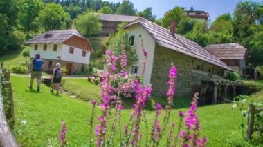 Bir erkek ve bir kadın, güneşli bir öğleden sonra Slovenya 'nın Prevalje kentindeki eski değirmeni ziyaret ediyor.