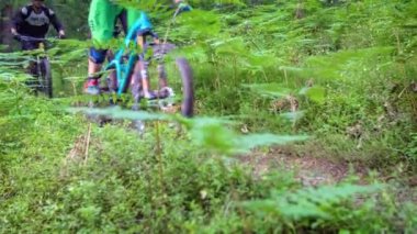 Ormanda bisiklete binen iki dağ bisikletçisi. Alçak açı yakın çekim takip.