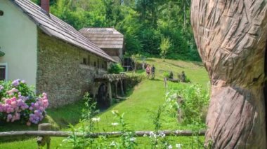 Genç yürüyüşçüler Slovenya 'nın Polhov Mill kentinde dönen su çarkı boyunca yürüyorlar