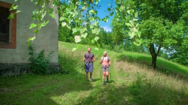 Rückwärts Fahrendes Wanderndes Paar Passiert Kirche Grüner Landschaft — Stockvideo