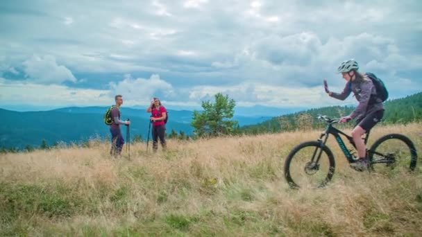 Bergwanderer Und Wanderin Stehen Auf Dem Gipfel Während Mountainbiker Vorbeifahren — Stockvideo