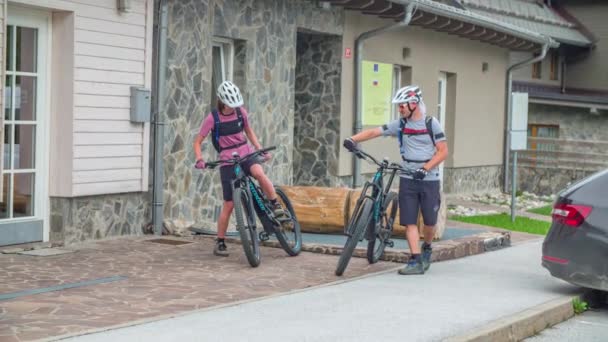若いカップルがマウンテンバイクやサイクルに乗る過去の建物 Handheld — ストック動画