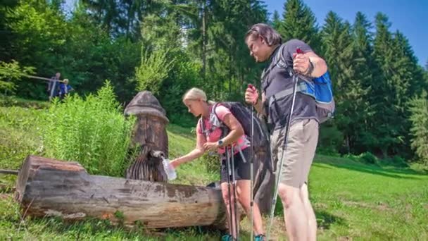 Vandrare Par Stannar Vid Trä Fontän Bergen För Att Dricka — Stockvideo