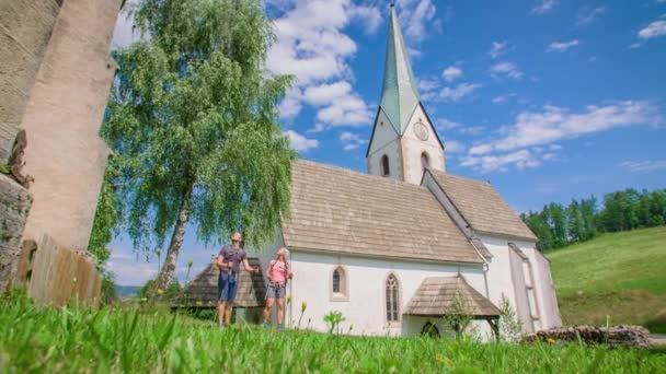 古い教会の建築や周辺の素晴らしい景色を楽しんでいるカップルのパンニングショット — ストック動画