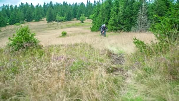 丘の上の田舎の荒野の風景の中にラフな道に乗る登山家 — ストック動画