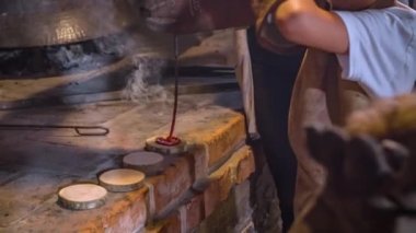 Küçük bir çocuğa yardım eden bir kadının kalbini küçük bir tahta parçasına kızgın demir çubukla işaretlemesine.