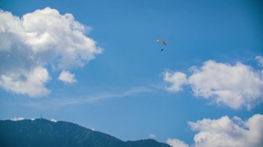 Paraglider Bulutlu Mavi Gökyüzüne Karşı Uçuyor Arka planda Ormanlı Dağ, Düşük Açı, Atışı Takip Et
