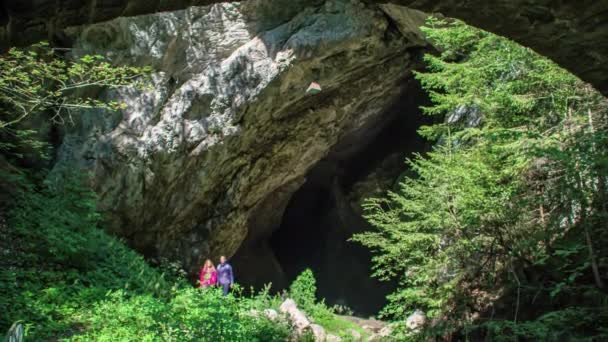 スロベニアのHuda Luknja洞窟の入り口を探索する若い大人のカップル — ストック動画