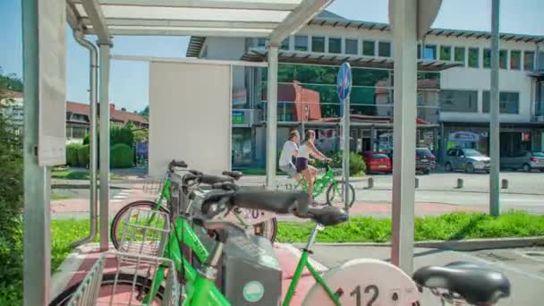スロベニアのラヴネ コロッセムで自転車共有システムを使用して若いカップル — ストック動画