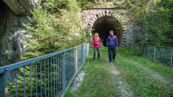 Pasangan Berjalan Melintasi Jembatan Keluar Dari Terowongan Berhenti Sejenak Untuk — Stok Video