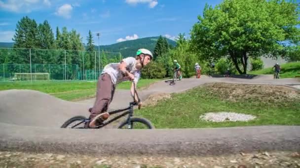 Grupp Barn Cyklar Och Skotrar Rida Runt Pumpspår Långsamma Rörelser — Stockvideo